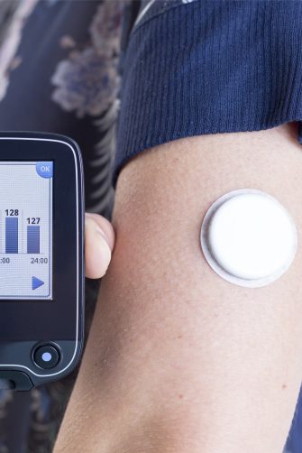 A young person showing a reader after scanning the sensor of the glucose monitoring system b