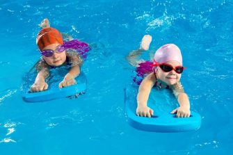 two young children swim with kickboards