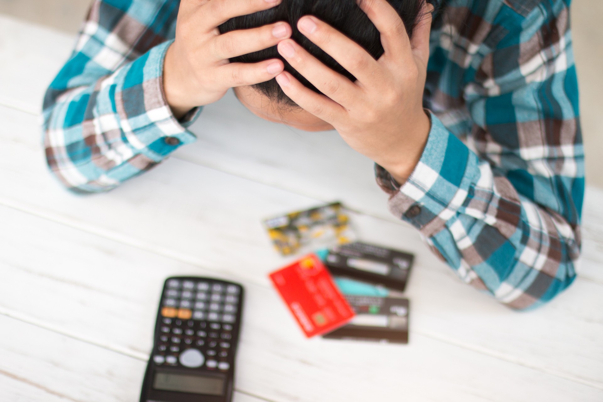 A woman worries with her head in her hands while looking at debit cards