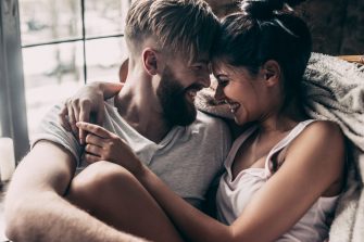 Young couple smiling and sitting face to face in chair 