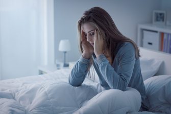 Person sitting awake in bed at night exhausted