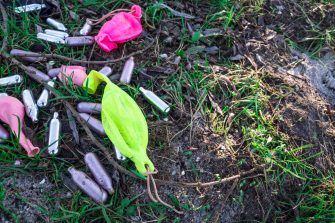 Spent nitrous oxide bulbs and baloons litter the grass