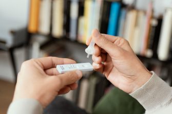 Picture of someone's hands placing their own sample into the covid-19 antigen diagnostic test device