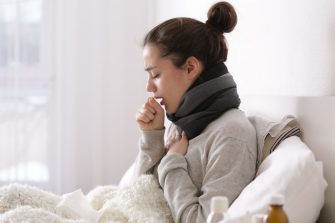 Young woman in bed coughing