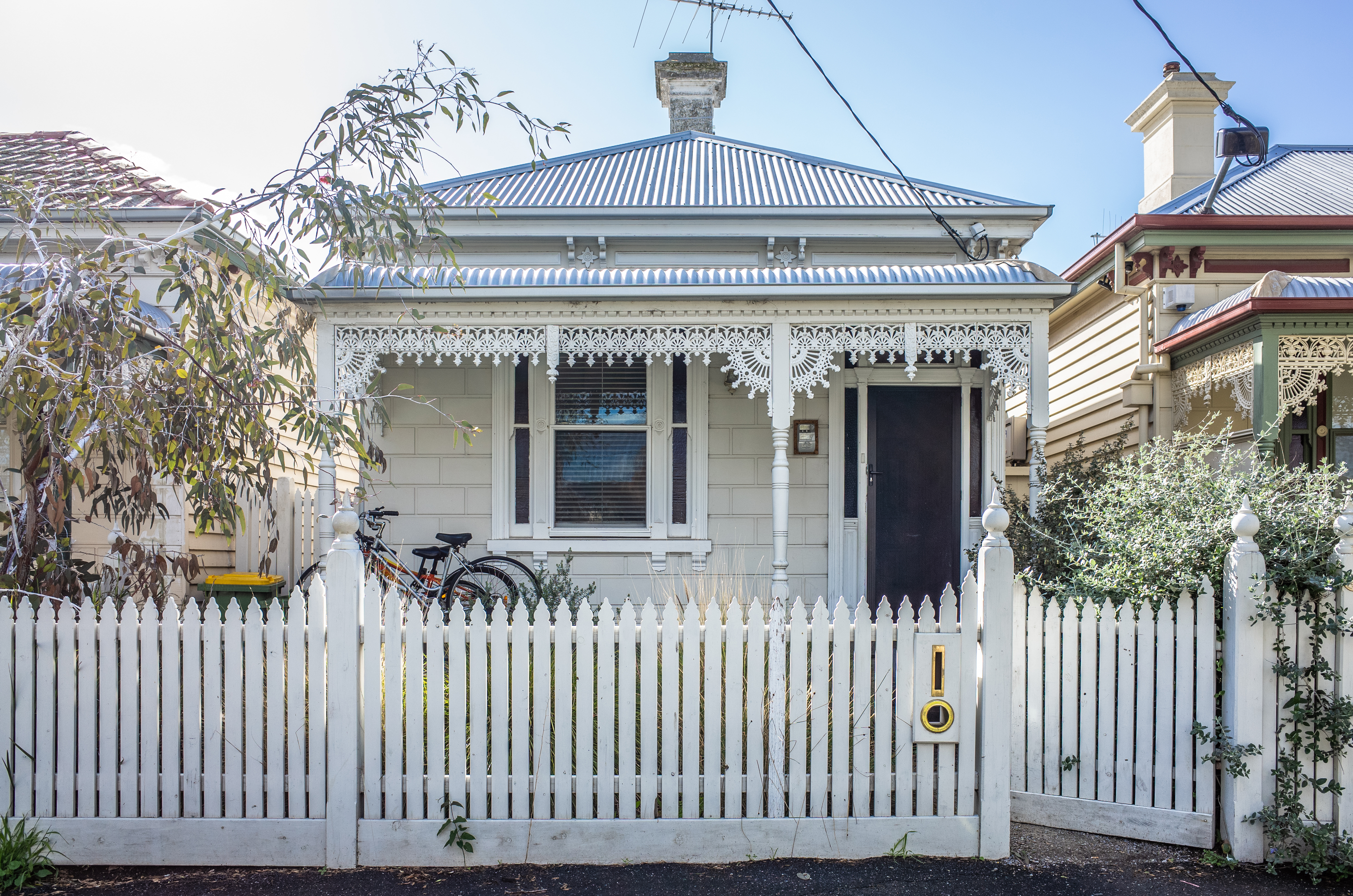 Corrugated iron house in Melbourne with a white fence in front of it