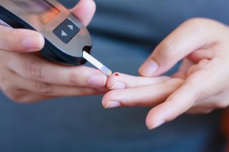 A person administering a finger prick to test blood glucose for diabetes