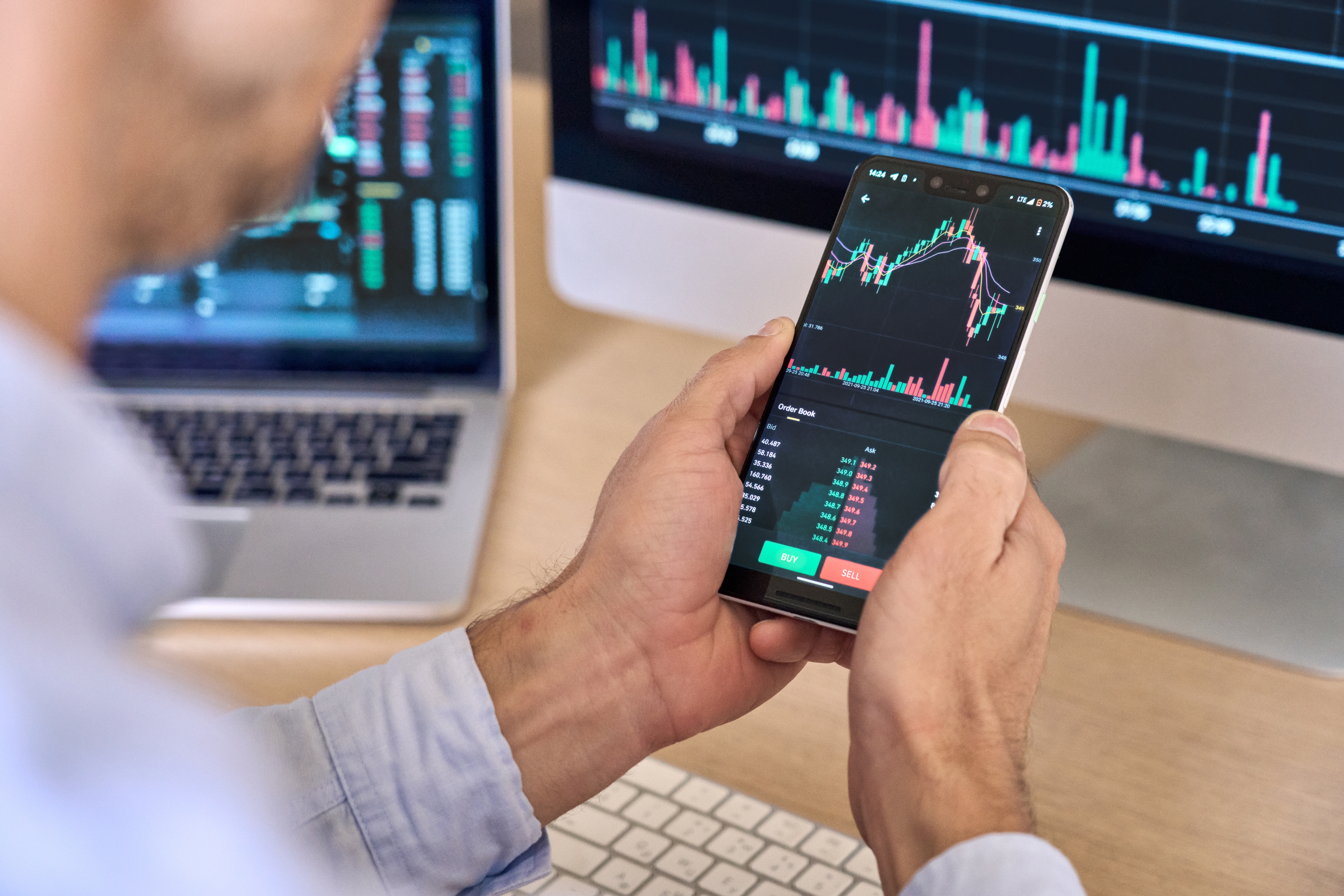 A man looks at his smartphone showing cryptocurrency fluctuations