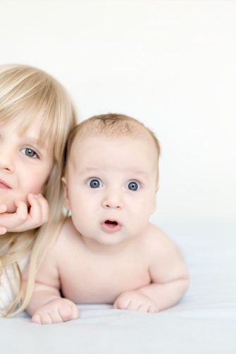 Portrait of brother and sister. Two cute children  lying on bed.  Open-eyed surprised or astonished expression. Brother and sister best friends, happy family and  childhood concept. 