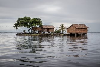 Traditional thatched houses on a small artificial island on a gloomy day in Lau Lagoon, off the island of Malaita in the Solomon Islands.