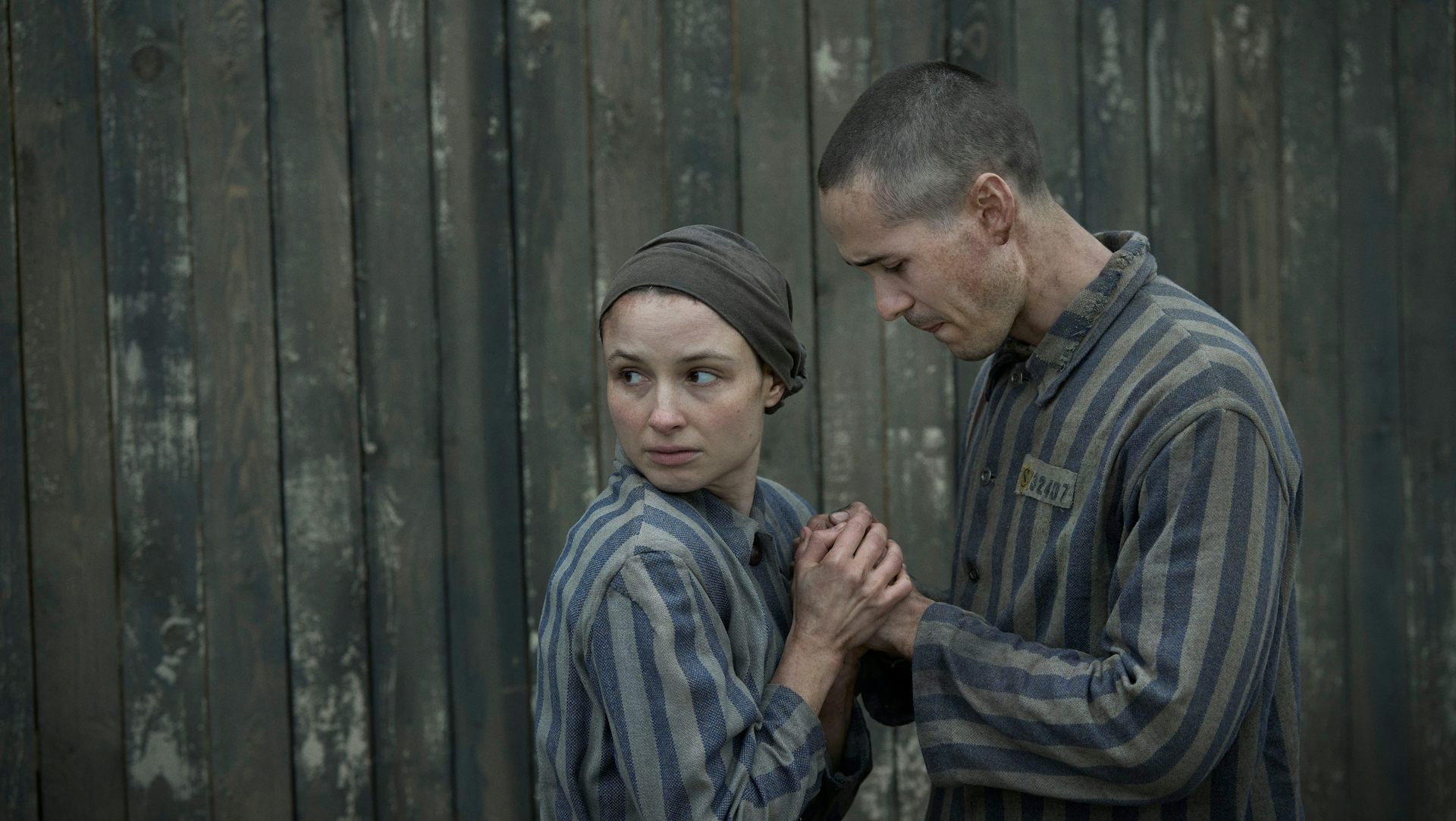 female and male Jewish prisoners at Auschwitz hold hands in fear 