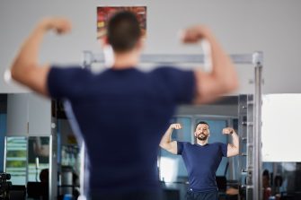 Muscular man examining his progress in the mirror at gym