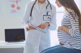Happy lesbian couple playing with their children at home. Beautiful family of four having great time together indoors.