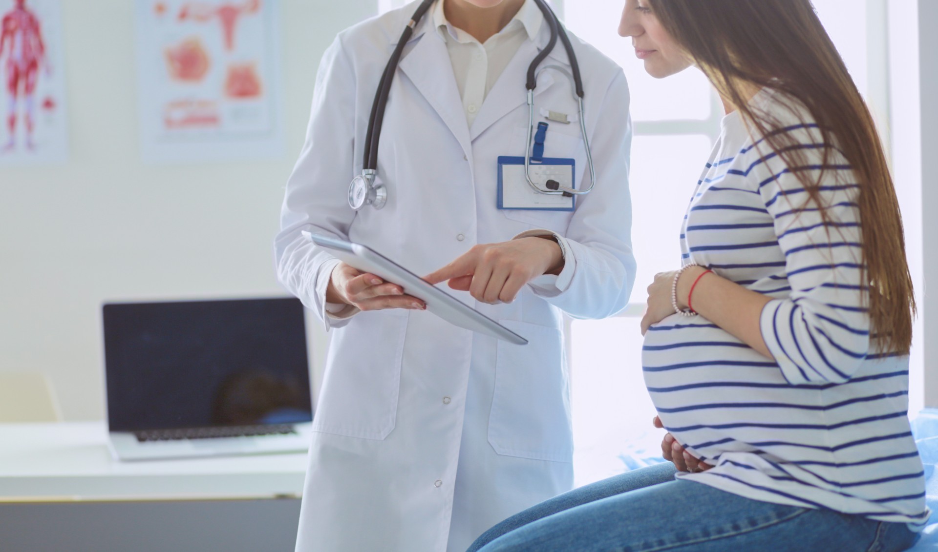 Smiling pregnant woman with the doctor at hospital.