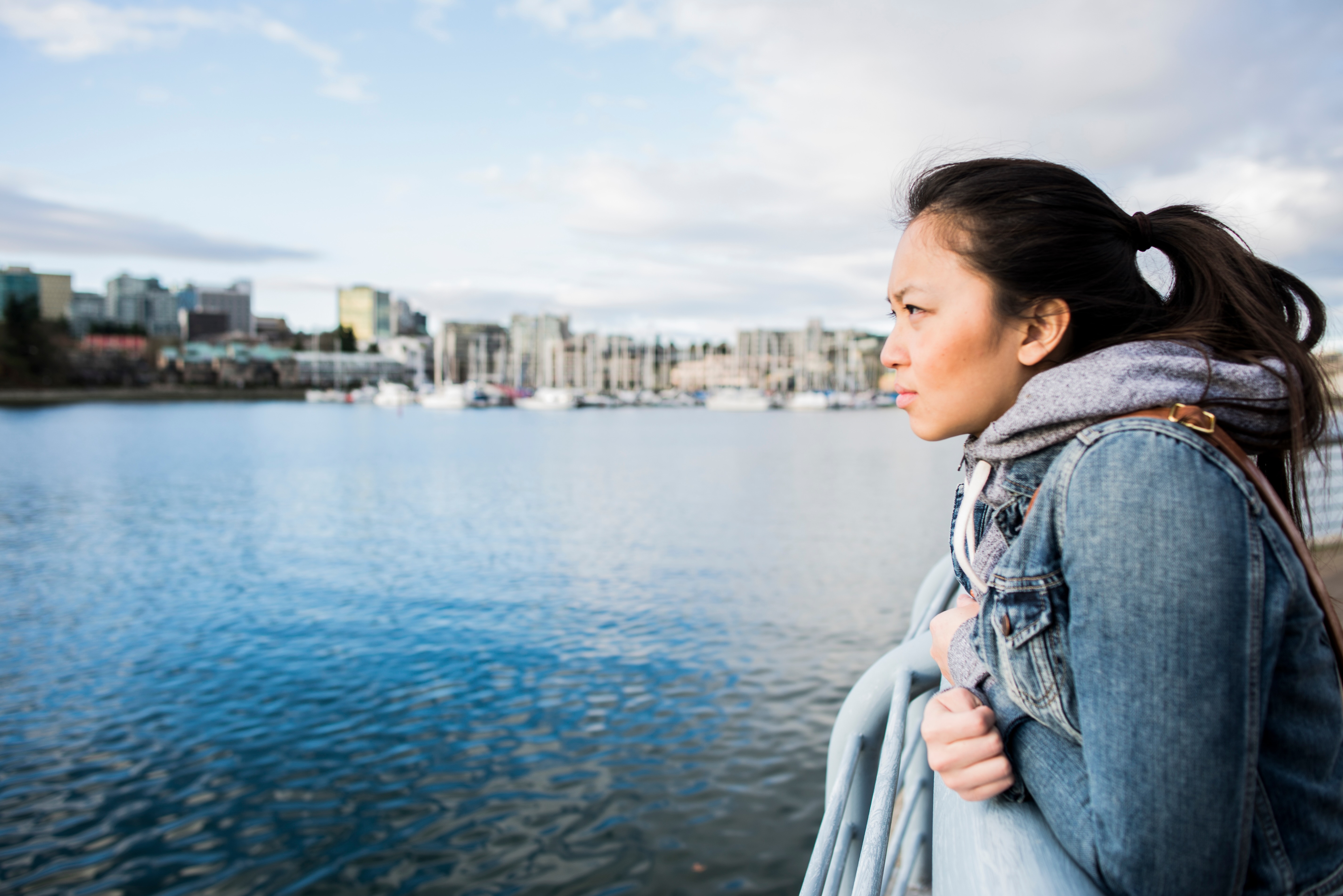 Young woman leaning against barrier, taking in view, Yaletown Ferrydock, Vancouver, Canada