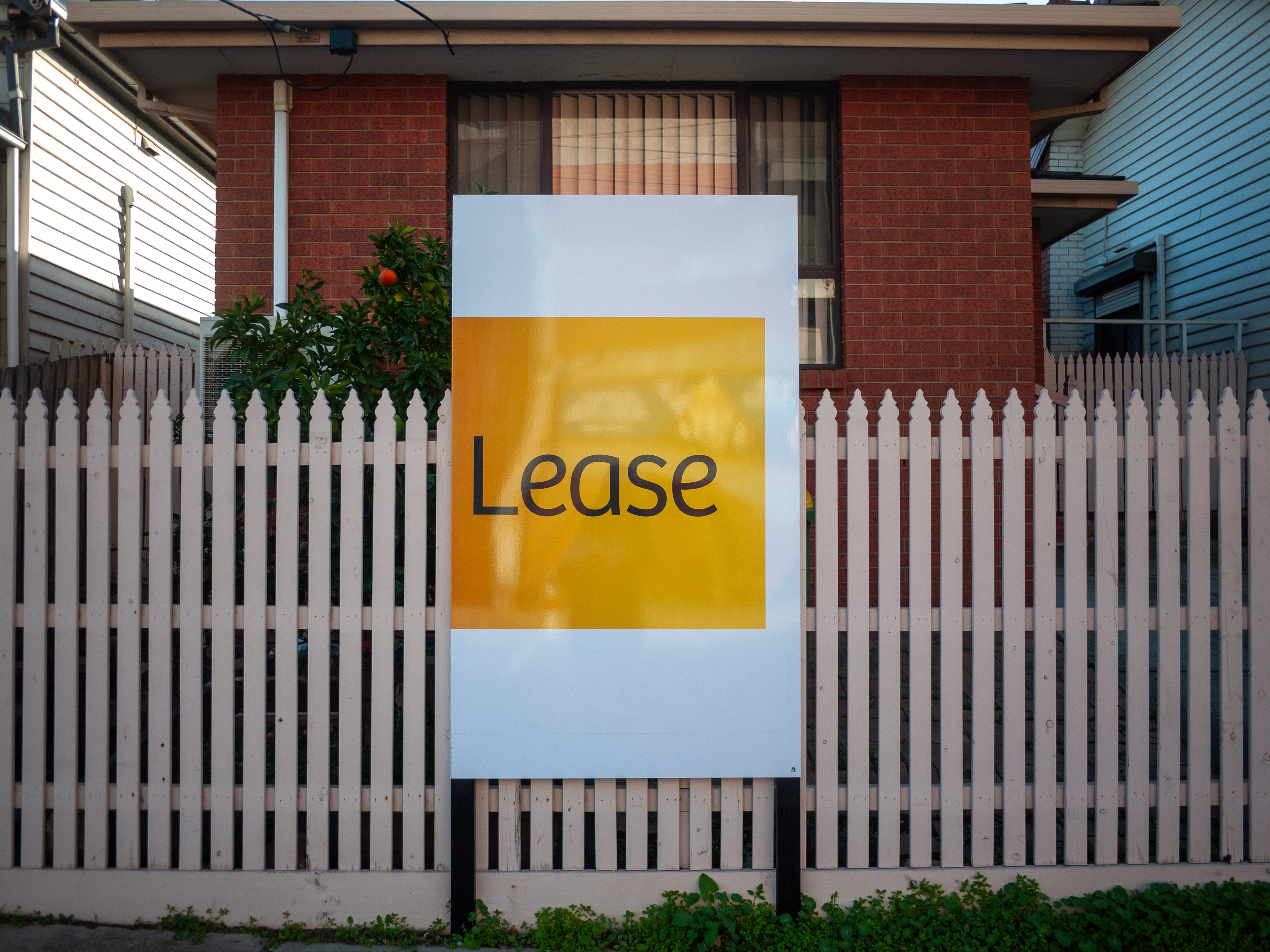 An advertisement sign for a residential property and suburban house listed for lease. Concept of the housing market, real estate, and renting a home.