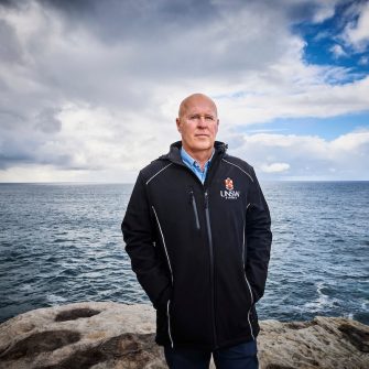 Photo of Professor Matthew England standing on a clifftop with the ocean in the background