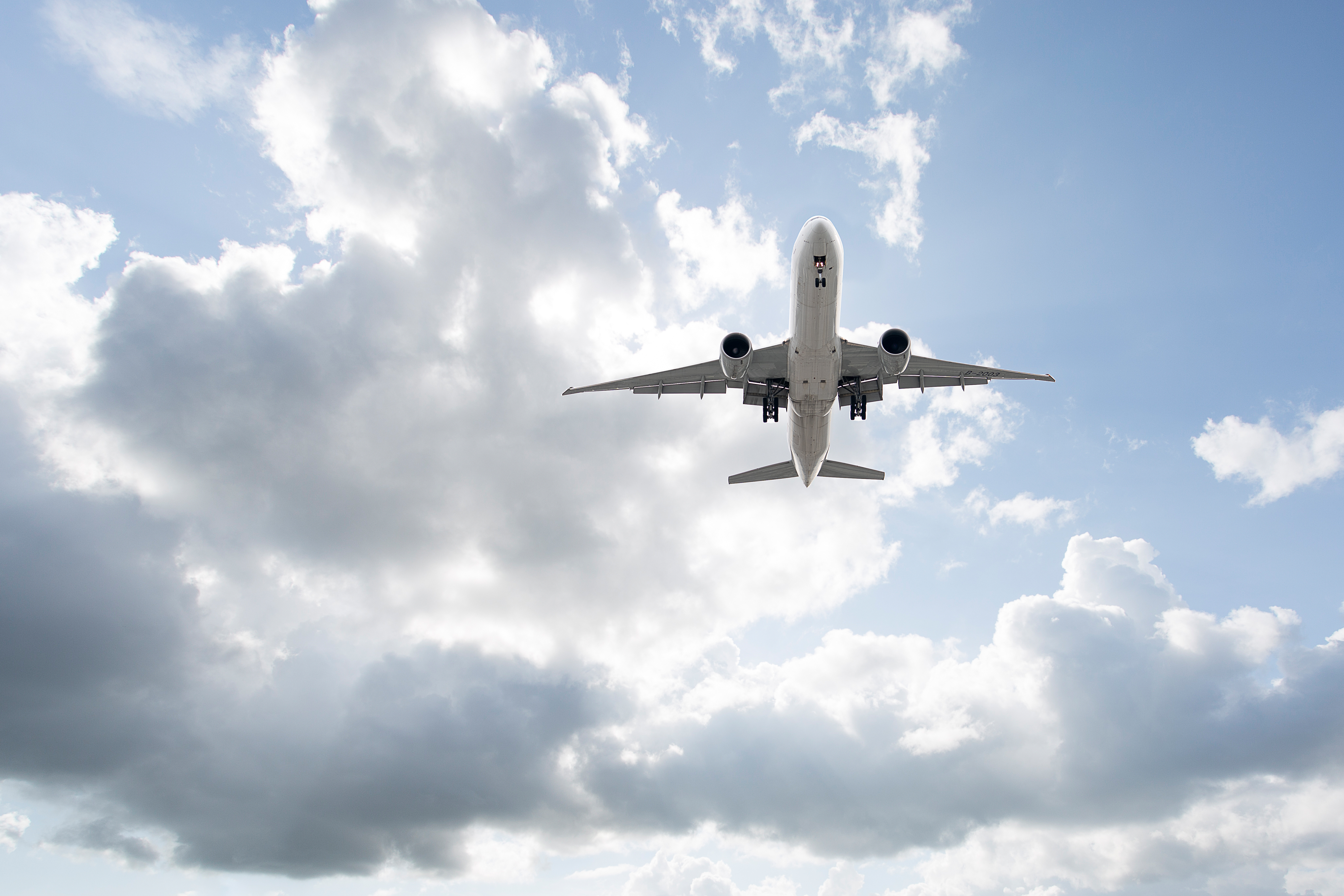jet airplane flying, traveling in the sky overhead from below the underside of the plane