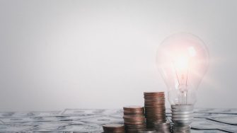 Gold coins growth in stack with light bulb