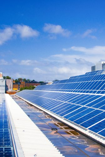 Rooftop solar panels in the foreground with UNSW Library in the background against blue sky