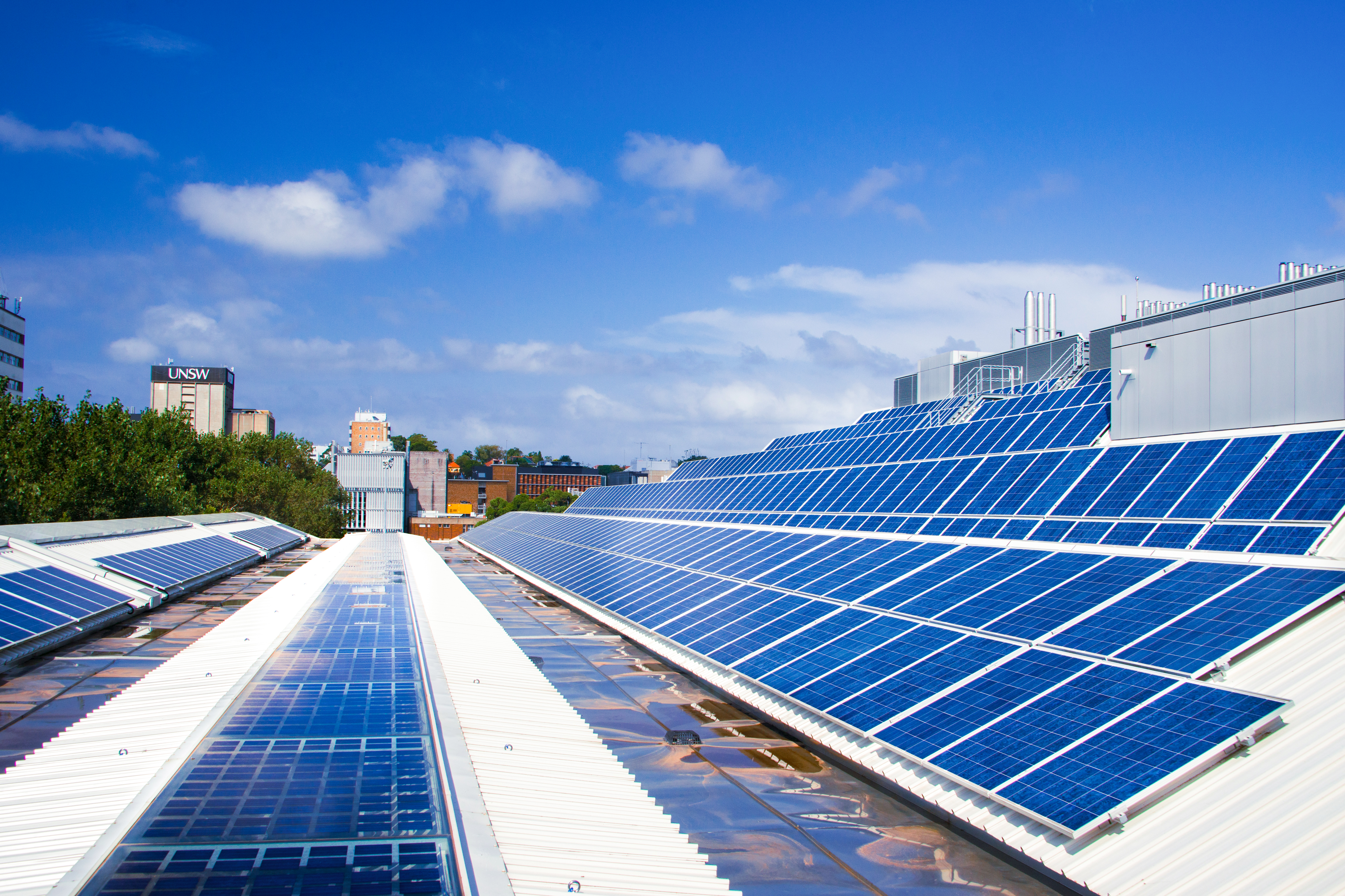 Rooftop solar panels in the foreground with UNSW Library in the background against blue sky