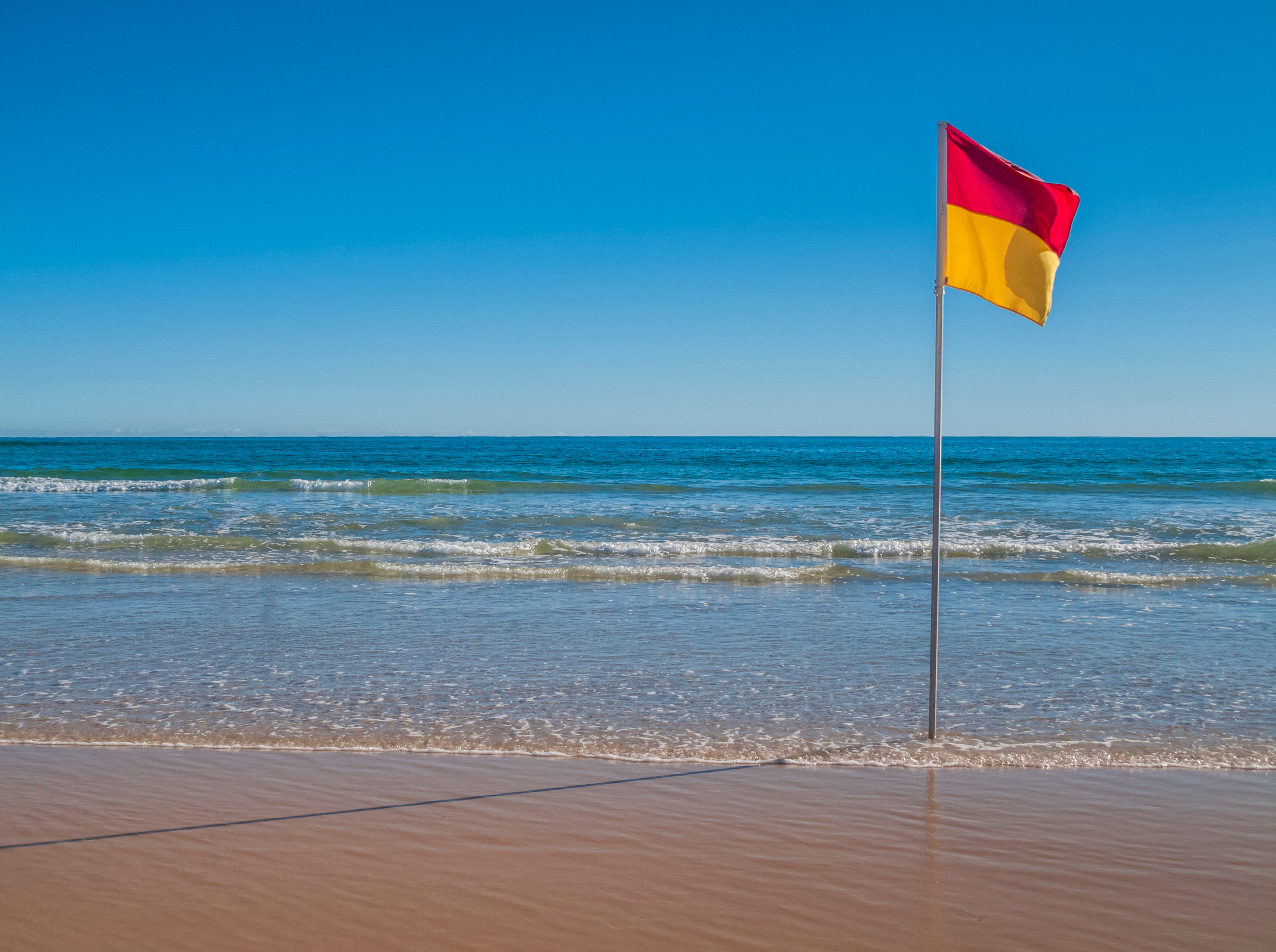 Beachscape with red and yellow flag indicating safe, patrolled beach in Australia