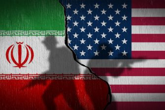 National flags of USA and Iran on a cracked stone wall with soldier silhouettes. Concept of Middle East tension and nuclear war.