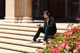 Japanese male student sitting on the steps and studying 