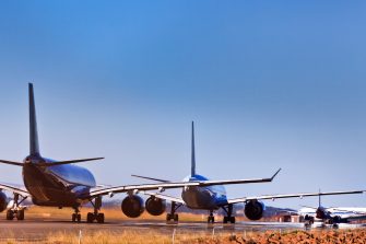 5 commercial airplanes lining up on runway of airport airfield waiting for departure. Clear sky above Sydney International airport and land jet traffic.