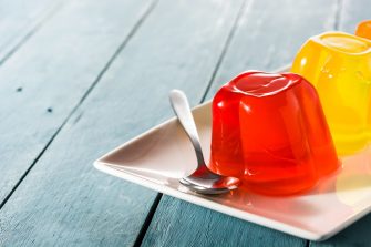 Colorful jelly on a plate on blue wooden background.