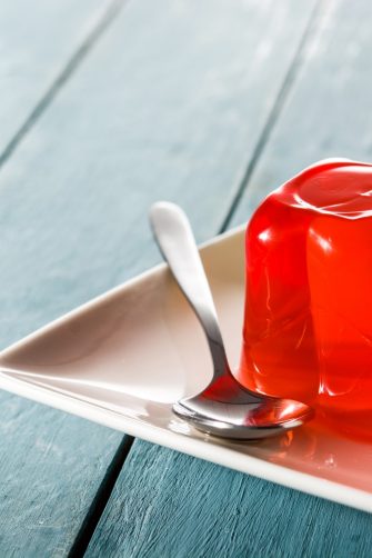 Colorful jelly on a plate on blue wooden background.