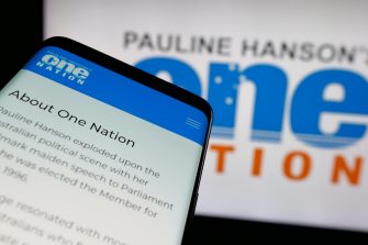 Mobile phone with website of Australian party Pauline Hanson's One Nation on screen in front of logo. Focus on top-left of phone display.