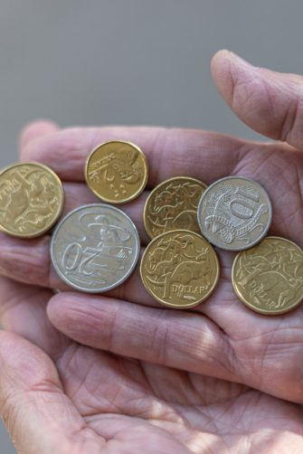 A few Australian dollar coins held on a man's hand, in the sun.