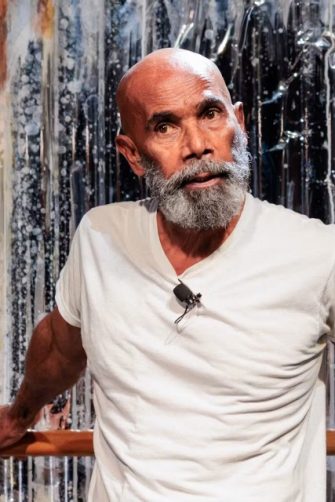An older Aboriginal man with a grey beard performs onstage