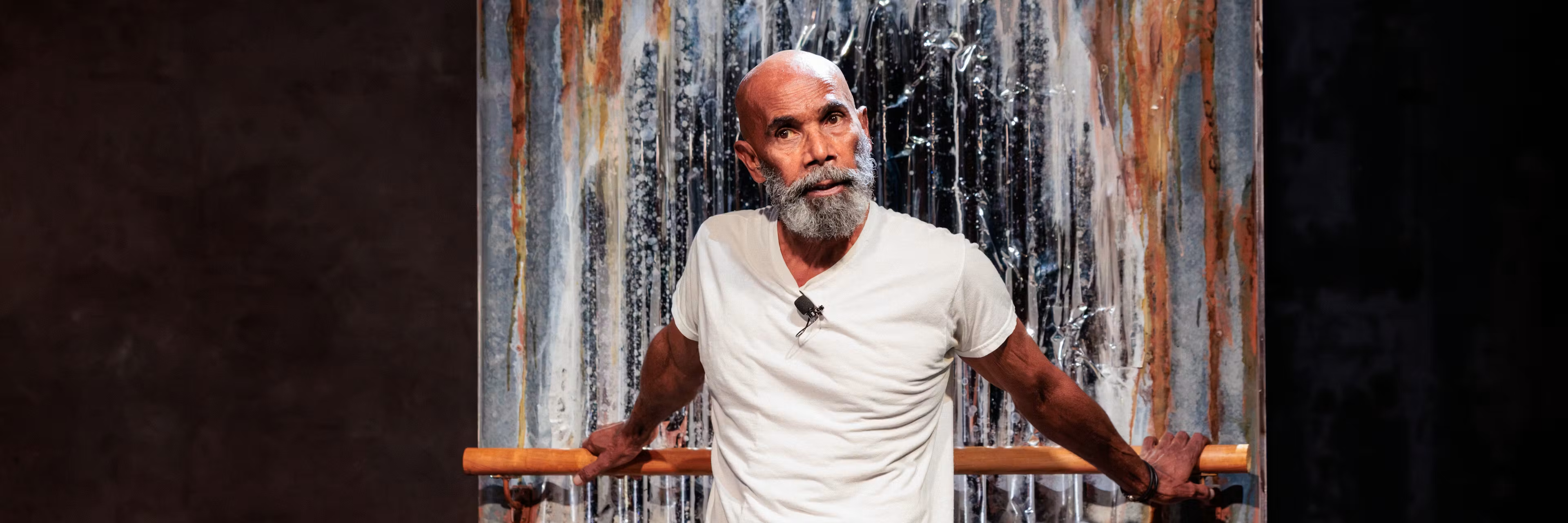 An older Aboriginal man with a grey beard performs onstage