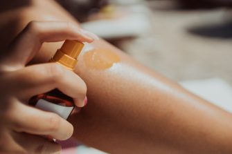 Woman uses spray tan on the beach
