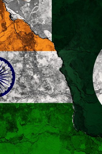 Concept of a Conflict between India and Pakistan with painted flags on a wall with a crack