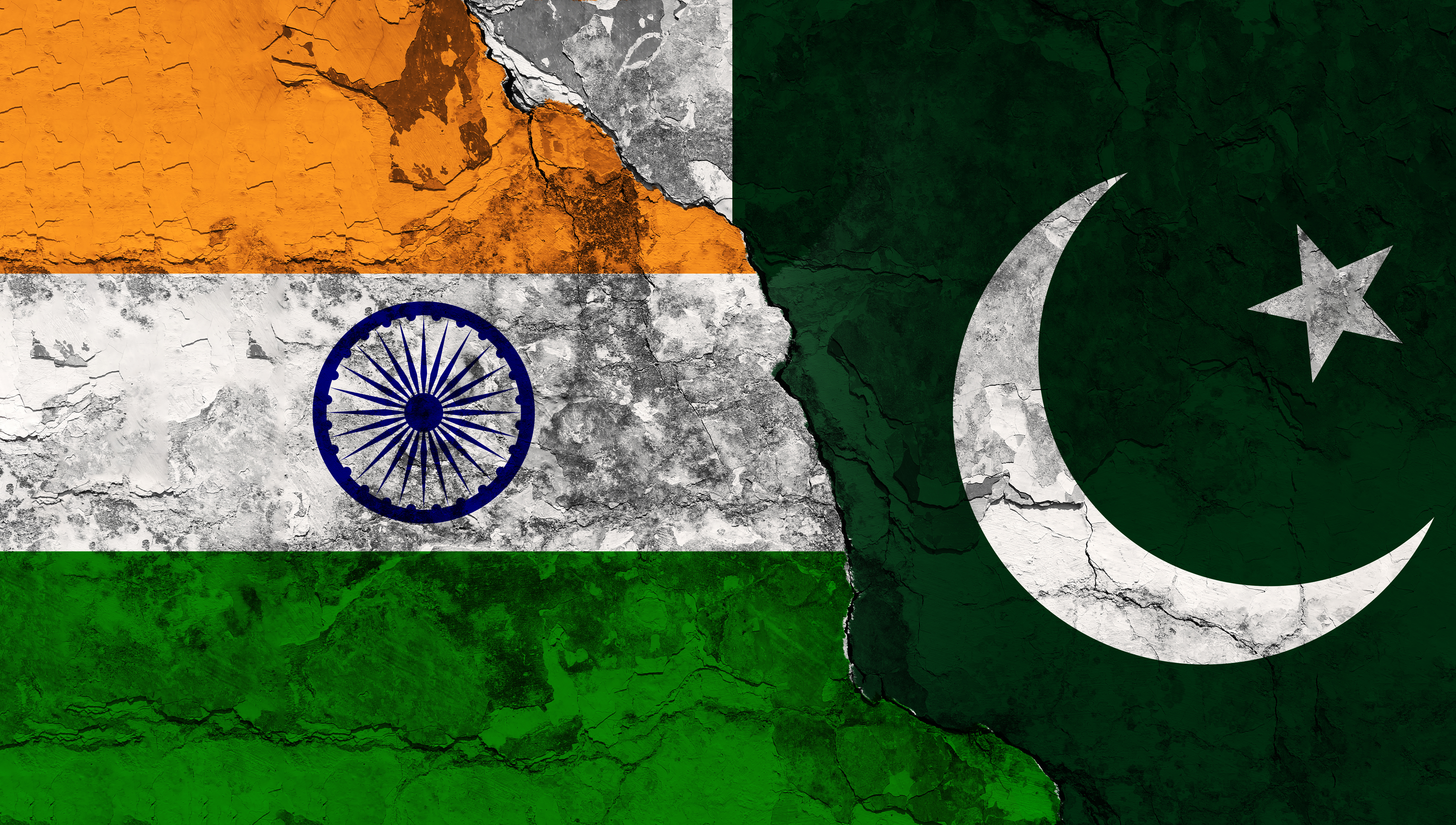 Concept of a Conflict between India and Pakistan with painted flags on a wall with a crack