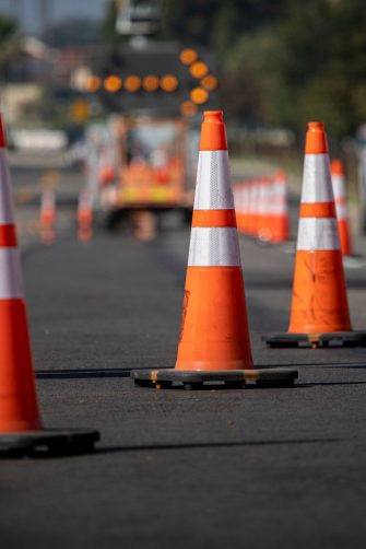 Traffic cones on road with electronic arrow pointing to the right to divert traffic and white car in distance