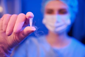 Closeup of embryologist hand in sterile glove holding sealed cryovial with cryopreserved biological material
