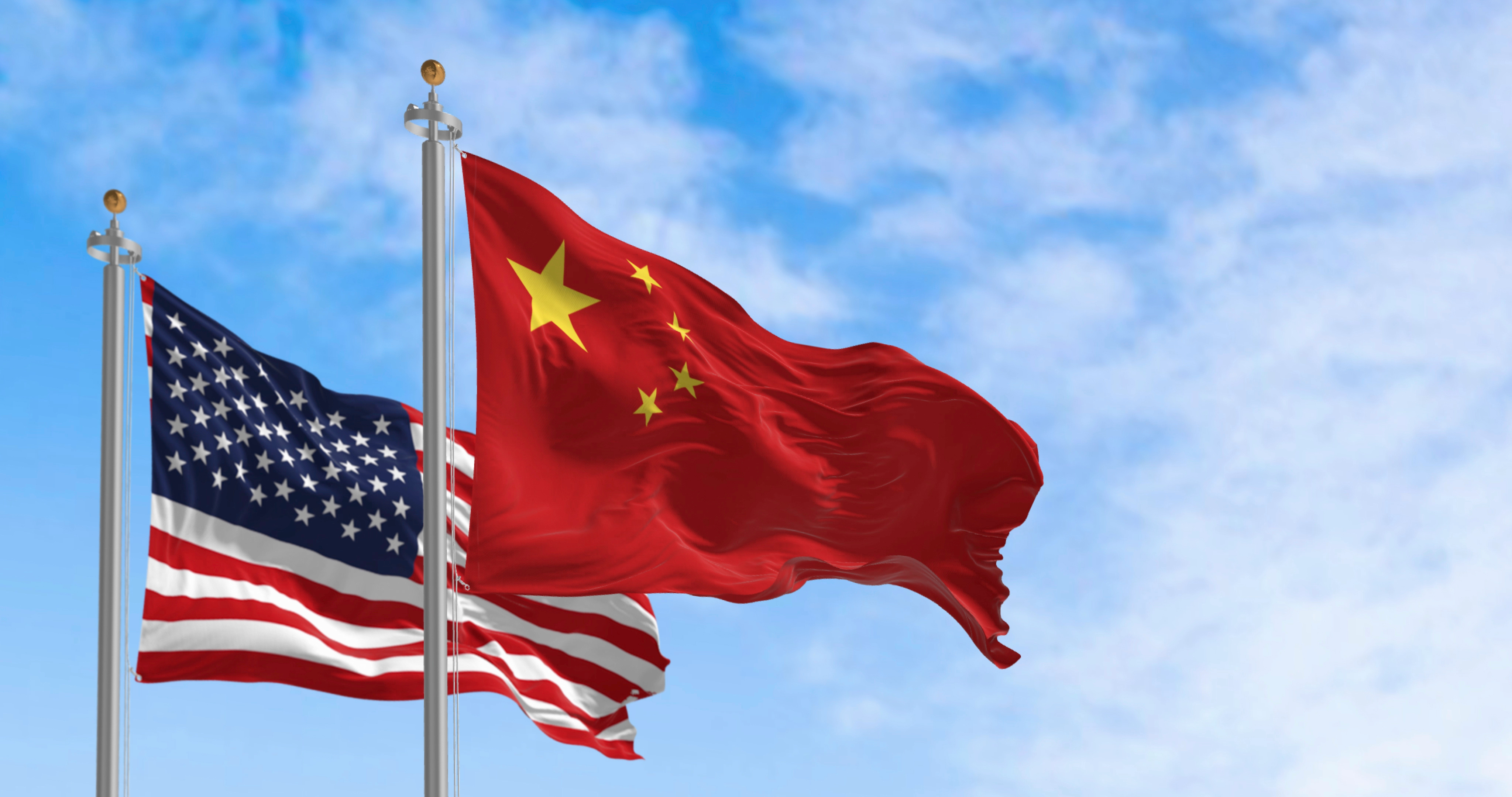 National flags of China and the United States waving in the wind on a clear day. International relationship. 3d illustration render. Selective focus.