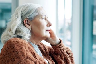 Senior woman looking pensively out window