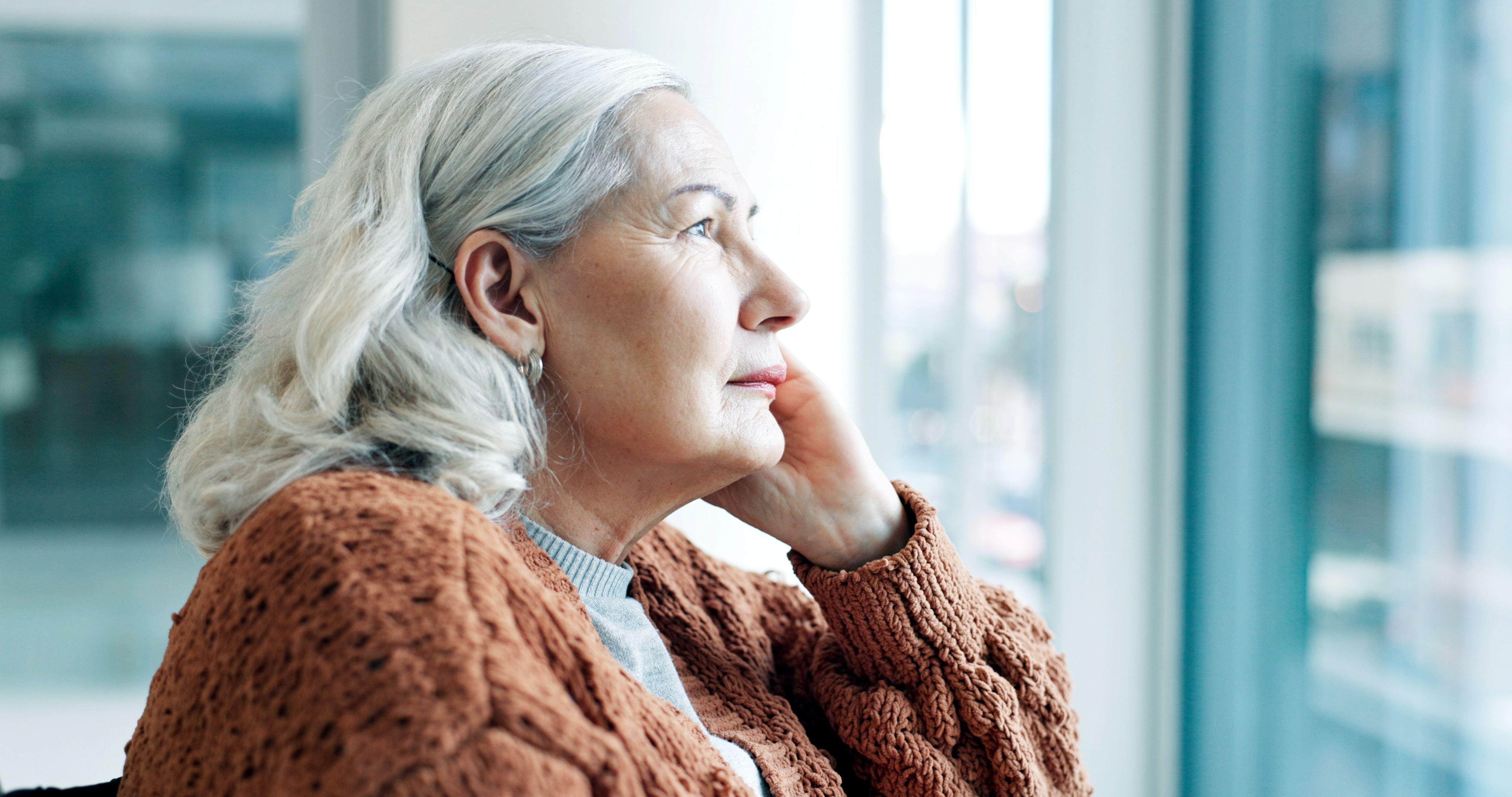 Senior woman looking pensively out window