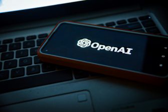 OpenAI logo on a mobile phone sitting on a laptop keyboard