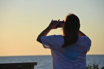 Woman taking photo on her phone at a beach
