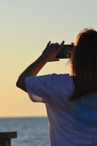 Woman taking photo on her phone at a beach