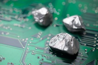 Mineral rare earth element on green electronic circuit board background copy space. US vs China chip war, tech war, semiconductor industry concept. China curbs on exports of rare earth element to US.