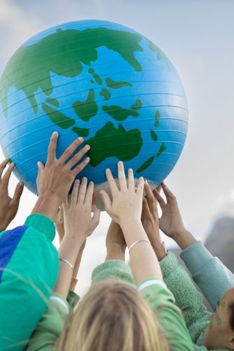 Manager using a digital tablet to check the operation of the solar panel system of a solar station. Female technician in reflective clothing holding a tablet PC standing by solar grid at solar farm.