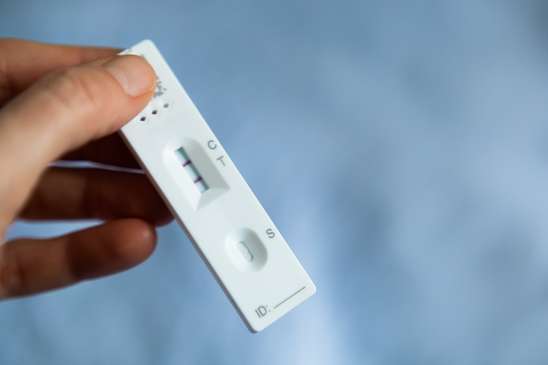 Positive Cassette rapid test for COVID-19. Close-up shot of woman's hand holding a negative test device.