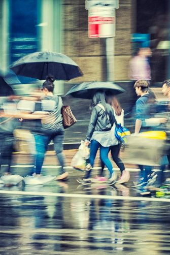 Rush hour commuters crossing the road during a wet day in Sydney. Cross processed image