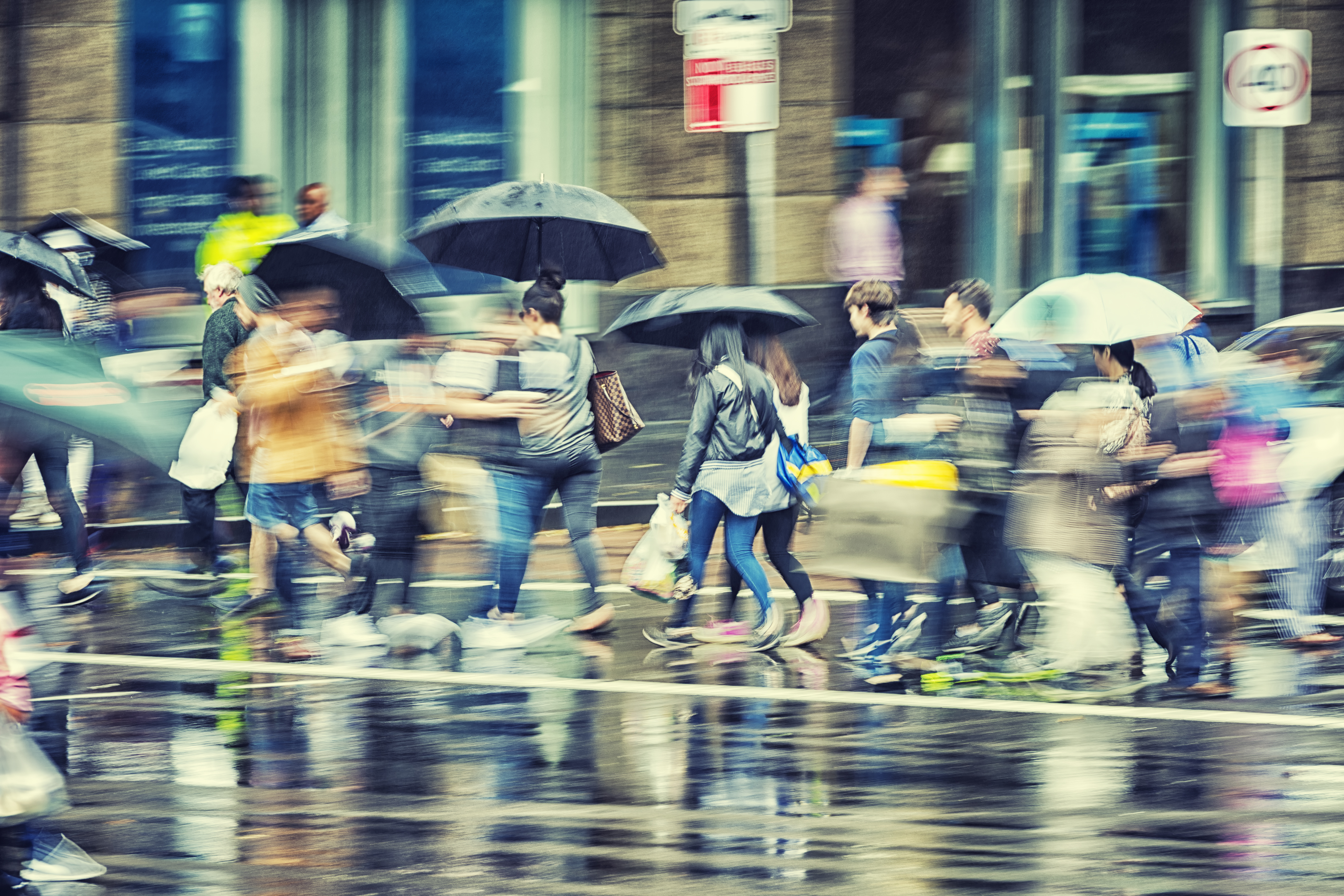 Rush hour commuters crossing the road during a wet day in Sydney. Cross processed image